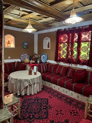 a living room with a red couch and a table at Auberge Lwalida in Ouled Sguir