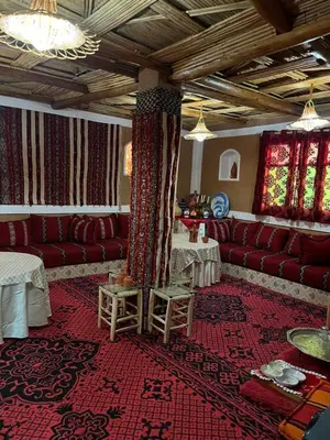a living room with red couches and tables at Auberge Lwalida in Ouled Sguir
