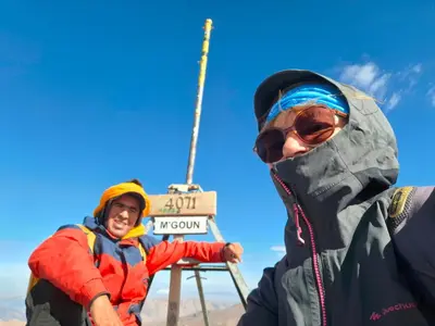 two people in jackets standing next to a sign at Gite d'étape La terre Amazigh in Oulad Akkou