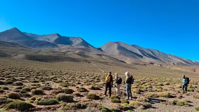 a group of people standing in the desert with mountains in the background at Gite d'étape La terre Amazigh in Oulad Akkou