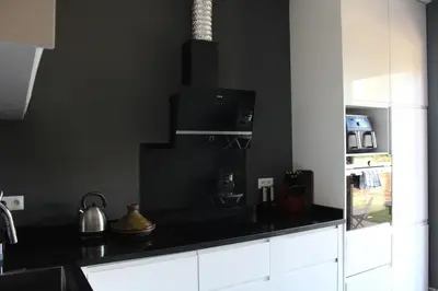 a kitchen with black walls and white cabinets at Villa Bakhta in Najem