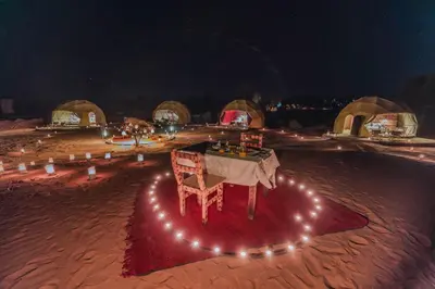 a table and a chair in a desert at night at Unique Desert Camp in Merzouga
