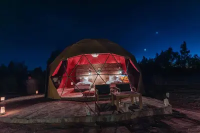 a tent with two chairs in it at night at Unique Desert Camp in Merzouga
