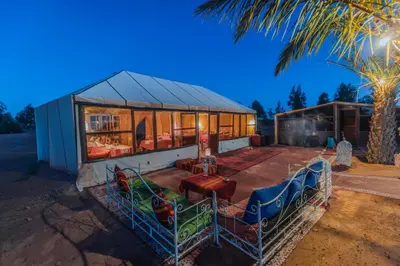 a house with a lot of windows and a palm tree at Unique Desert Camp in Merzouga