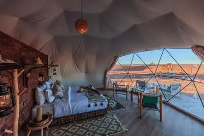 a bedroom in a tent with a view of the desert at Unique Desert Camp in Merzouga