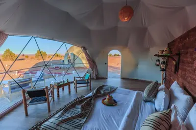 a bedroom with a bed in a tent with a view at Unique Desert Camp in Merzouga