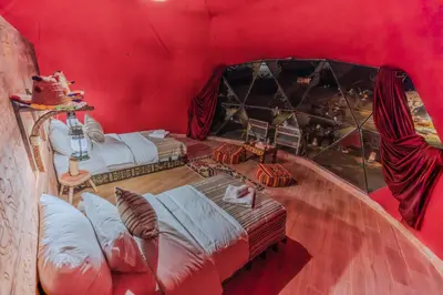a room with two beds and a red wall at Unique Desert Camp in Merzouga