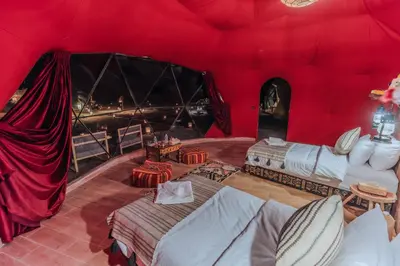 a room with a red tent with beds in it at Unique Desert Camp in Merzouga