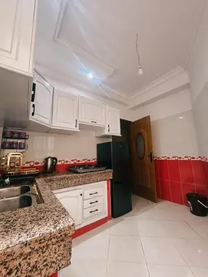 a kitchen with white cabinets and a red wall at Perfect Cozy Apartment in City Center Hamrya in Meknès