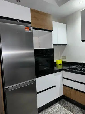a kitchen with white cabinets and a stainless steel refrigerator at شقة جميلة ومجهزة افران in Ifrane