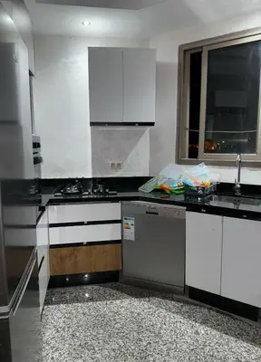 a kitchen with black and white counters and a dishwasher at شقة جميلة ومجهزة افران in Ifrane