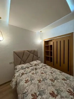 a bedroom with a large bed and two lights at شقة جميلة ومجهزة افران in Ifrane