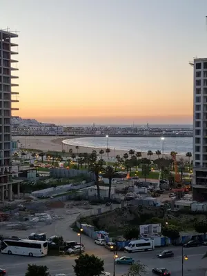 a view of a city with a beach at sunset at Seaside Serenity 5 Star Flat By Train Station in Oulad Akkou