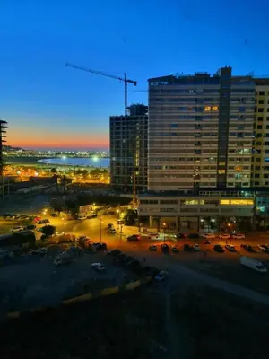 a city at night with cars parked in a parking lot at Seaside Serenity 5 Star Flat By Train Station in Oulad Akkou