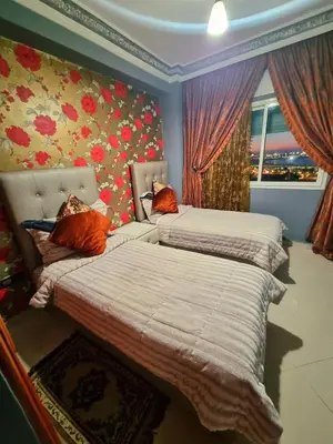 two beds in a room with flowers on the wall at Seaside Serenity 5 Star Flat By Train Station in Oulad Akkou