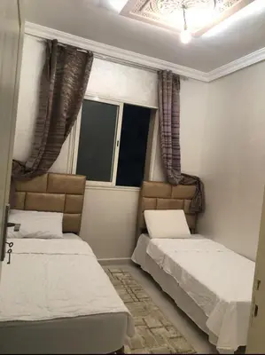 two beds in a small room with two windows at Apartment with beautiful view in the center of Marrakech in Oulad Akkou