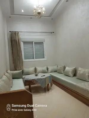 a living room with a green couch and a table at appartement complexe farah airoport in Oulad Akkou