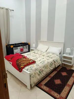 a bedroom with a white bed with a rug at appartement complexe farah airoport in Oulad Akkou