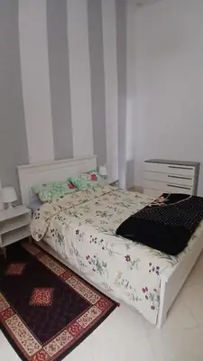 a bedroom with a white bed with a rug at appartement complexe farah airoport in Oulad Akkou