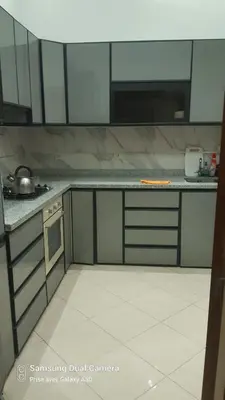 a kitchen with white cabinets and a white tile floor at appartement complexe farah airoport in Oulad Akkou