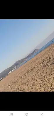 a beach with footprints in the sand and the ocean at Appartement à côté la plage in Oulad Akkou
