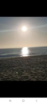 a beach with the sun rising over the ocean at Appartement à côté la plage in Oulad Akkou