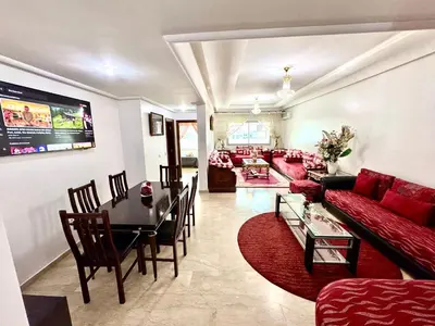 a living room with a red couch and a table at Appartement à proximité de tout ! in Fès