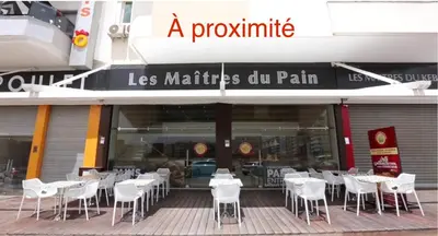 a restaurant with white tables and chairs in front of it at Appartement à proximité de tout ! in Fès