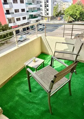 two chairs and a table on a balcony with green grass at Appartement à proximité de tout ! in Fès