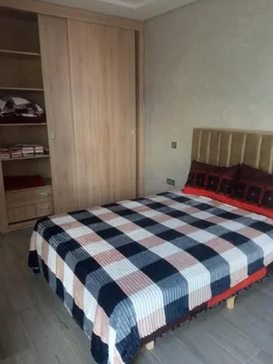 a bedroom with a bed with a checkered blanket at Villa Close to Lhdim Square in Meknès