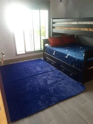 a bedroom with a blue rug and a bunk bed at Villa Close to Lhdim Square in Meknès
