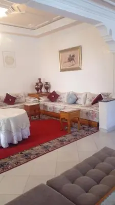 a living room with a couch and a red rug at Cosy villa in Oulad Akkou