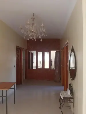 a living room with a chandelier and wooden doors at Cosy villa in Oulad Akkou