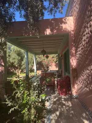 a patio of a pink house with awning at Villa Zaïtoun in Aït Ourir