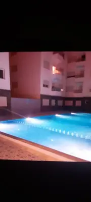 a blue swimming pool with buildings in the background at Appartement avec ,1 minte de la plage in Oulad Akkou