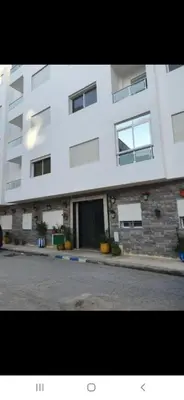 a large white building with windows on a street at Appartement avec ,1 minte de la plage in Oulad Akkou