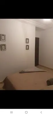 a bedroom with a bed with four pictures on the wall at Appartement avec ,1 minte de la plage in Oulad Akkou