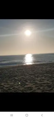 a beach with the sun rising over the ocean at Appartement avec ,1 minte de la plage in Oulad Akkou