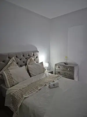 a bedroom with a large white bed with a dresser at Le Nid Doré, Appartement Chic au Centre de Meknès in Meknès