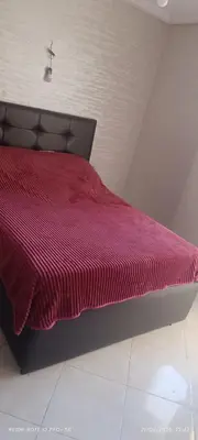 a bed with a red comforter in a room at apartment raha in Oulad Akkou