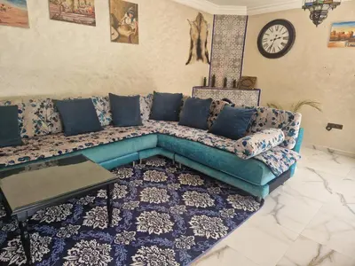 a living room with a blue couch and a clock at Villa Jenate Serenitée et paix in Timalizèn