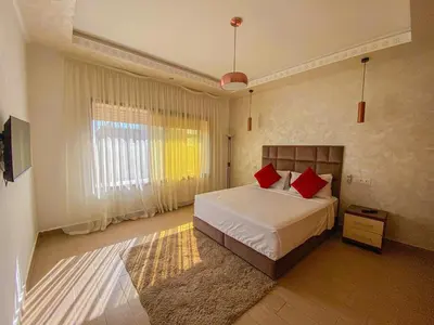 a bedroom with a bed with red pillows on it at Villa de luxe à louer Marrakech in Ourika