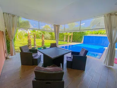 a room with a table and chairs and a swimming pool at Villa de luxe à louer Marrakech in Ourika