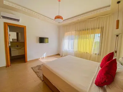 a bedroom with a large white bed with red pillows at Villa de luxe à louer Marrakech in Ourika