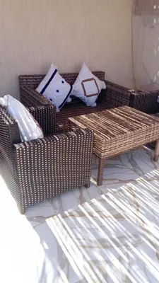 a living room with a wicker couch and pillows at Villa tagmouti in Aghmat