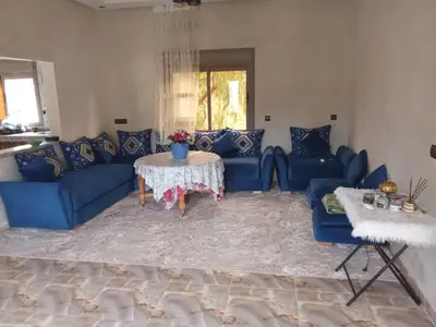 a living room with blue couches and a table at Villa tagmouti in Aghmat