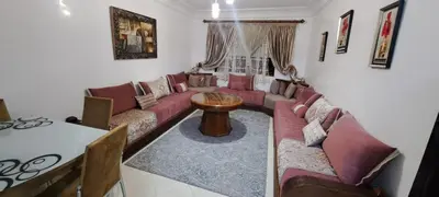 a living room with red couches and a table at حي السلام أكادير in Oulad Akkou