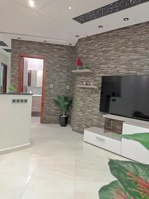 a living room with a large flat screen tv on a brick wall at حي السلام أكادير in Oulad Akkou