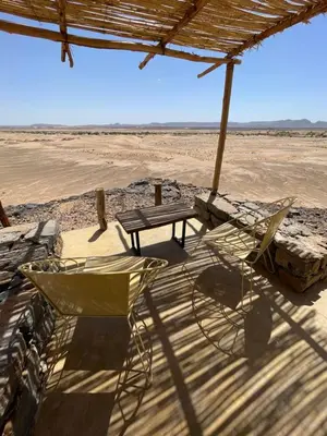a table and chairs sitting under an umbrella in the desert at Dunes Clave in Hassilabied