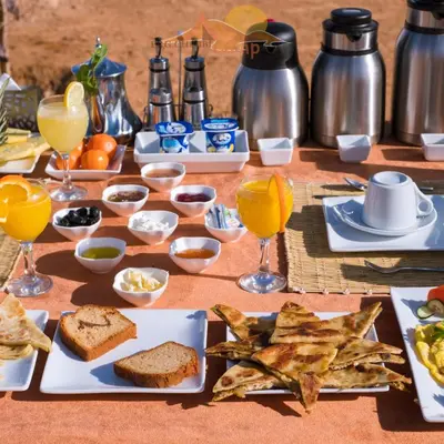a table topped with plates of food and glasses of orange juice at Dunes Clave in Hassilabied